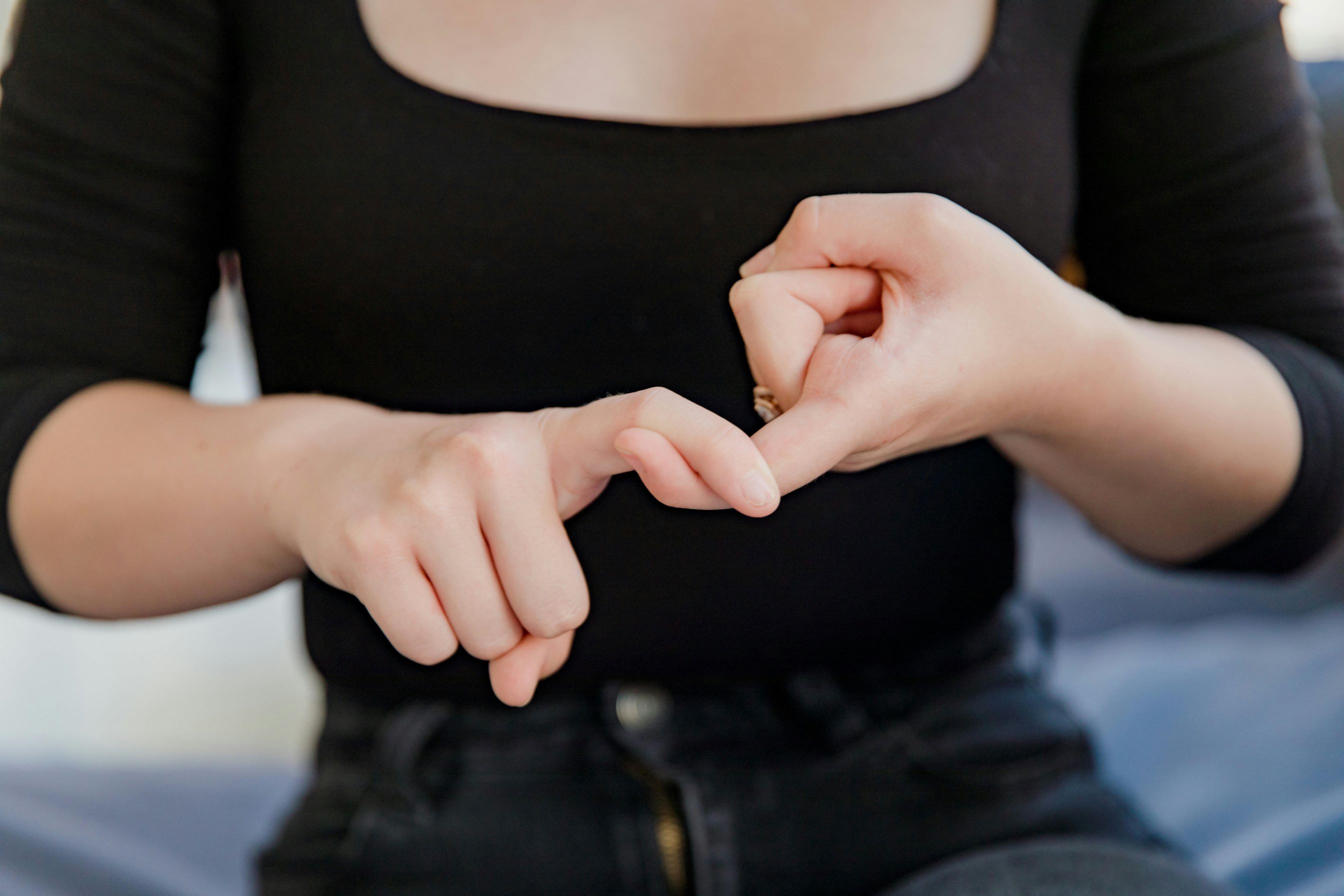 Young woman signs the word friend in American Sign Language.